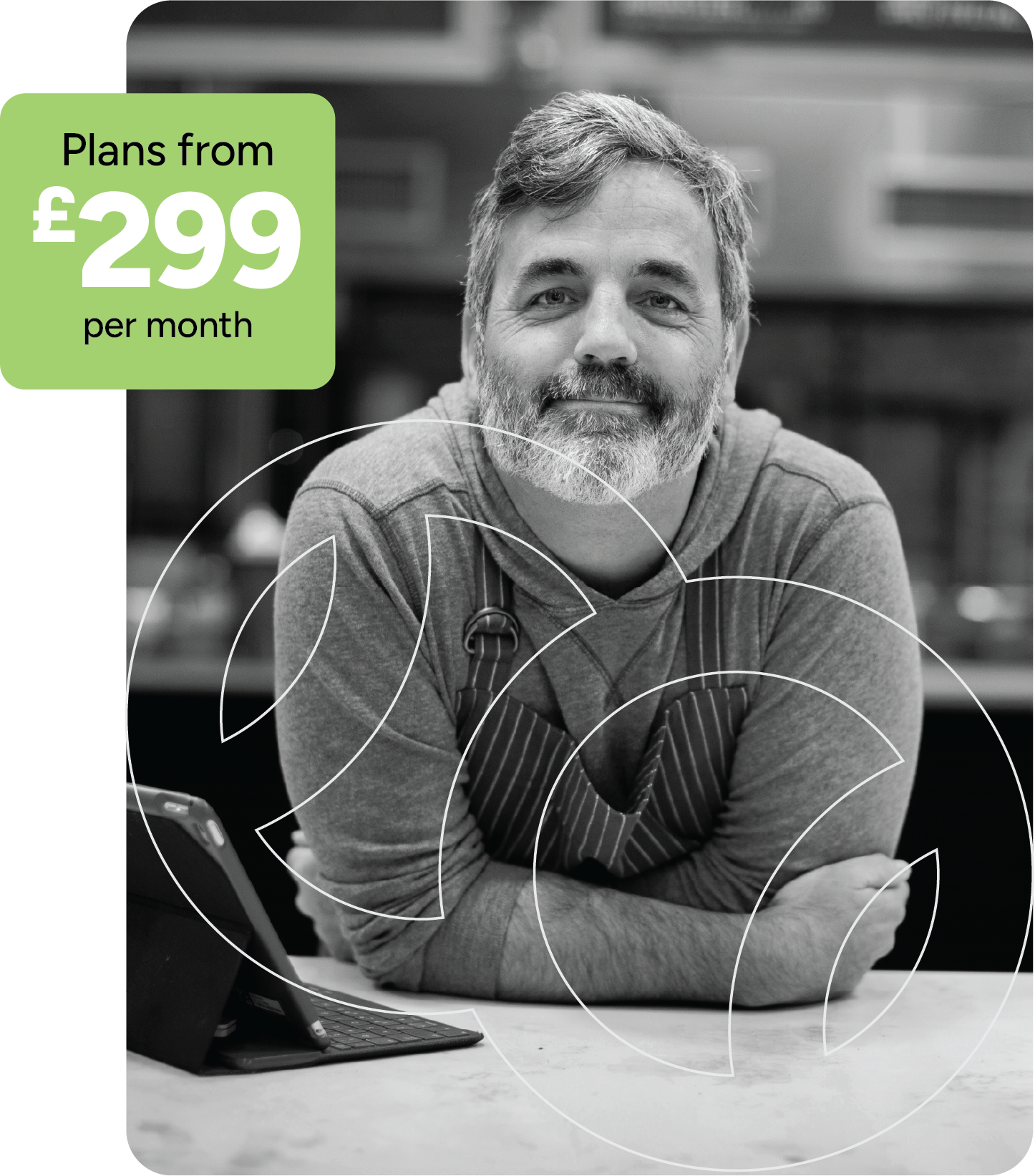 A smiling man in a gray hoodie with an apron, leaning on a countertop with a tablet, promoting design plans starting from £299 per month.
